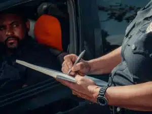 Police officer writing a ticket for a driver during a roadside check, highlighting enforcement measures against drunk driving.