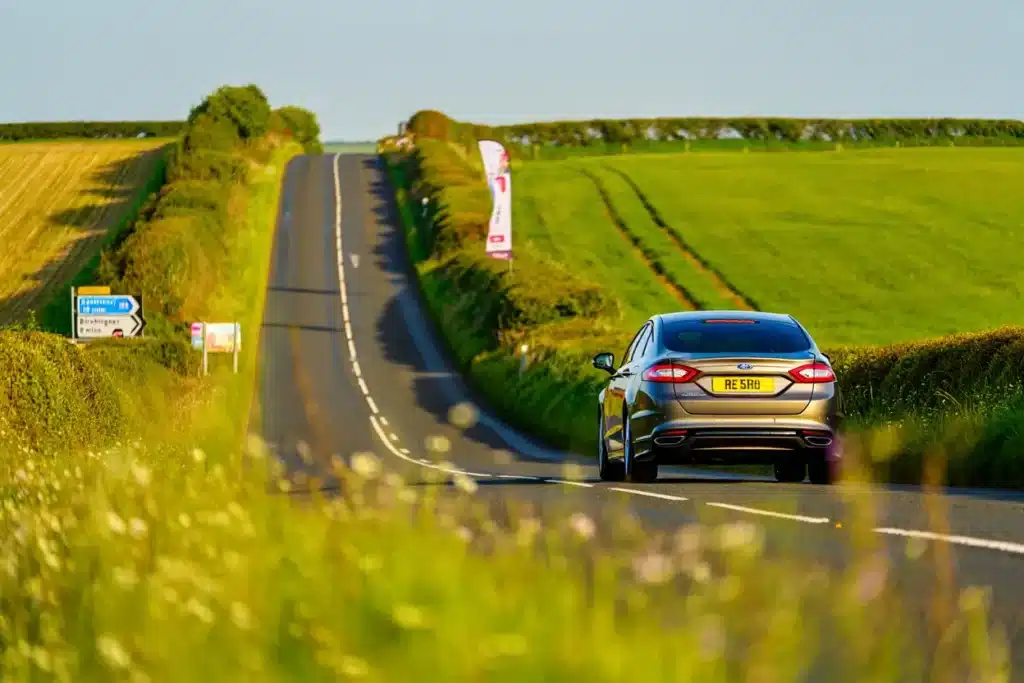 A car driving through the Kent countryside under blue skies, symbolising freedom to explore Kent’s newest 2026 attractions with a hire car.