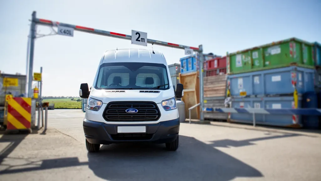 Short wheelbase white van approaching a Medway recycling centre entrance with a 2-metre height barrier.